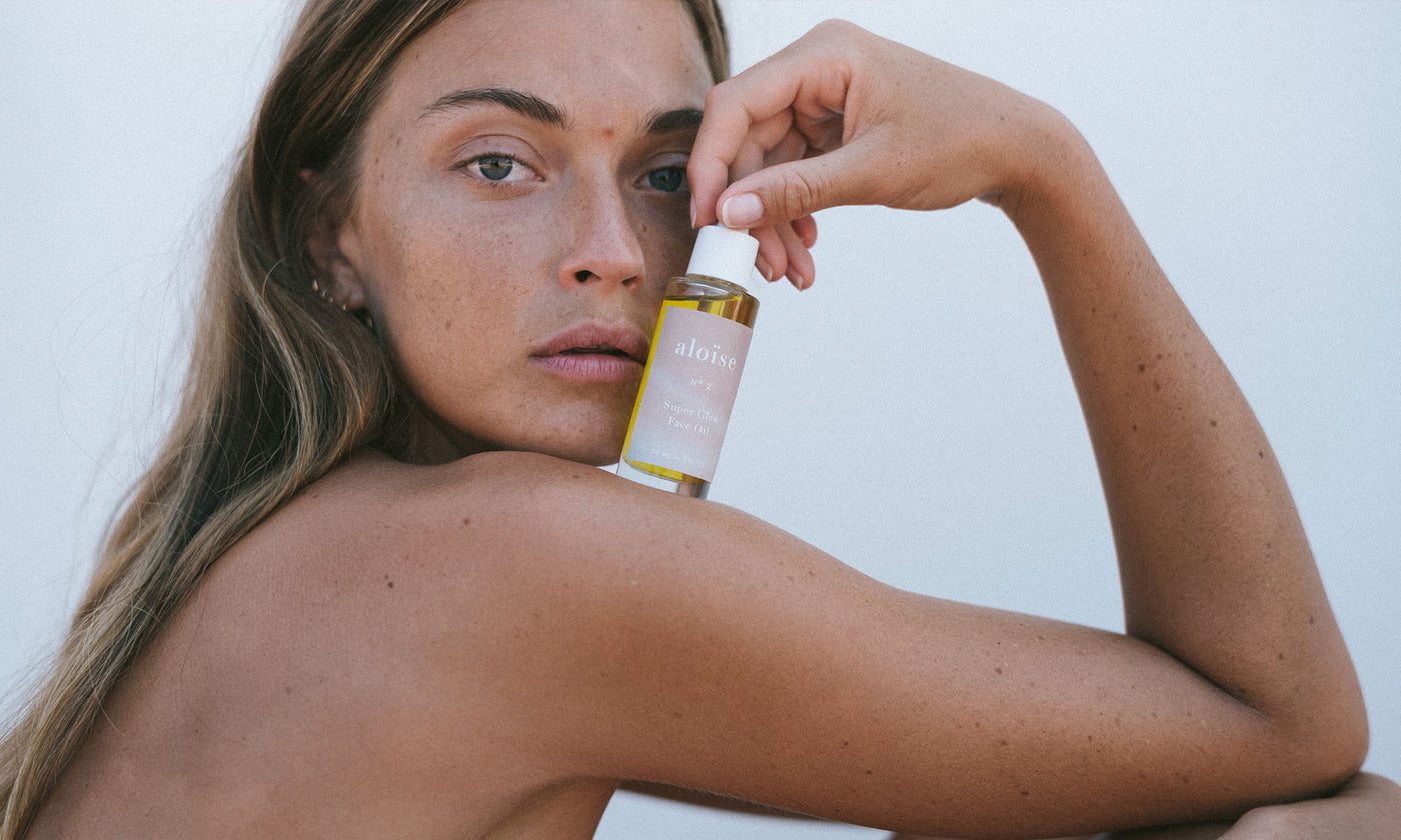 Model with Aloïse Super Glow Face Oil in her hand.