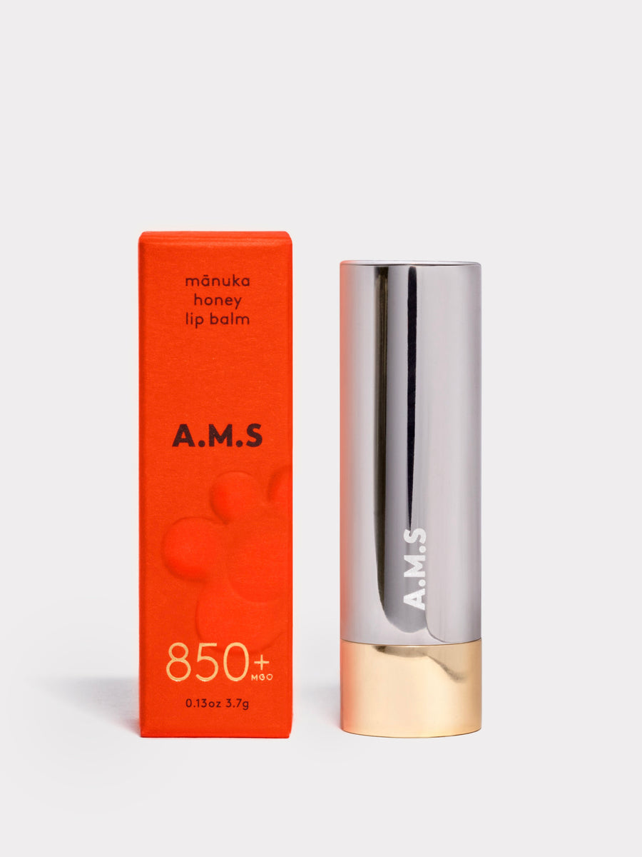 A.M.S manuka honey lip balm with red packaging and silver and gold applicator on a white background