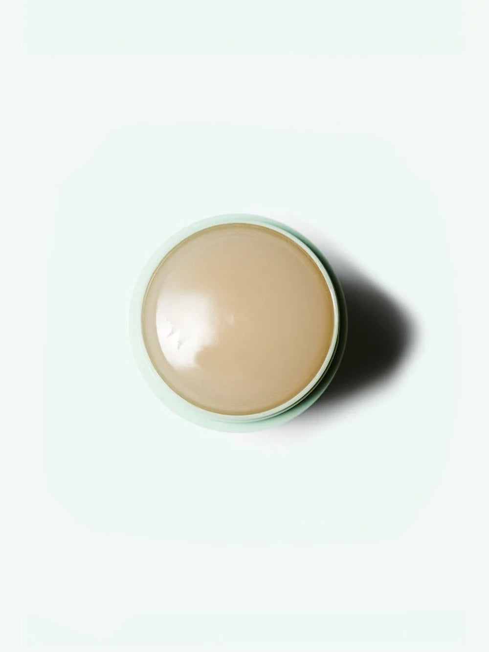 Green deodorant stick in a round container on a white background