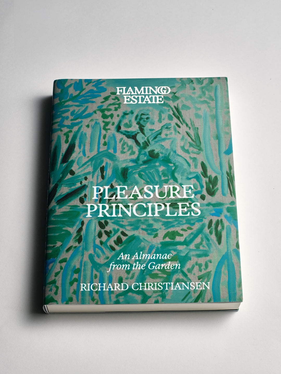 A hardcover book titled 'Pleasure Principles: An Almanac from the Garden' by Richard Christiansen, published by Flaming Estate. The cover features a vibrant turquoise and green botanical pattern with white text.