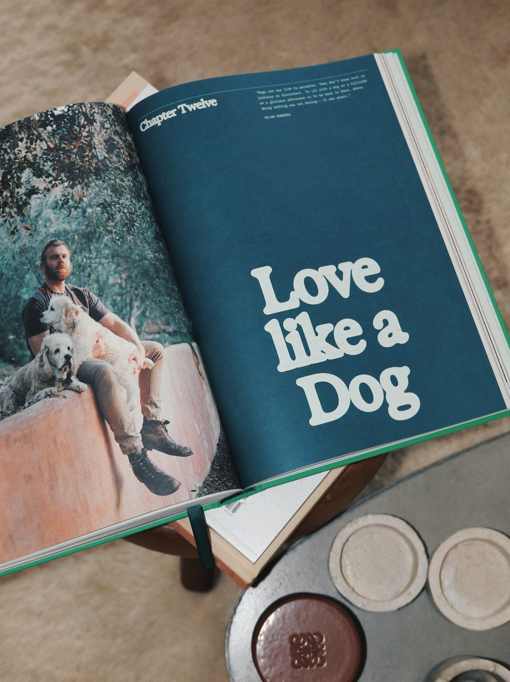Open book with a photo of a man and two dogs on one page and 'Love like a Dog' text on the other, on a wooden surface.