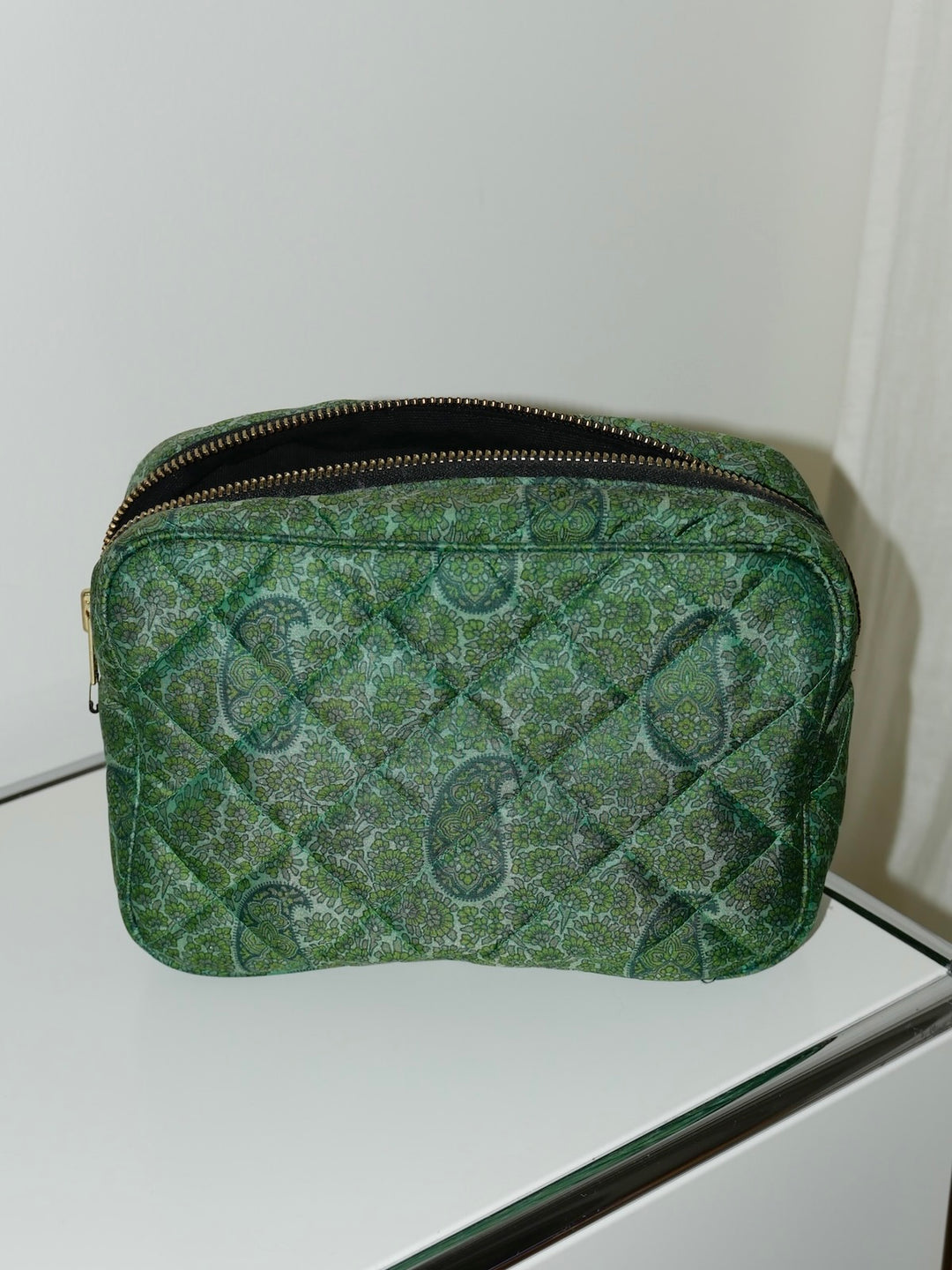 Green textured pouch with a brand logo on a white surface