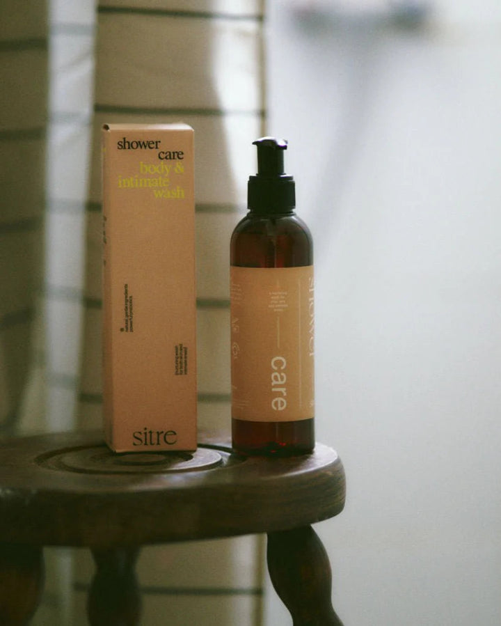 Bottle and box of Sitre shower care product on a wooden stool with a blurred background
