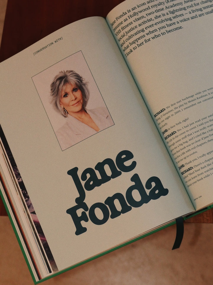 Open book with a portrait of a woman and the name 'Jane Fonda' on a wooden surface.