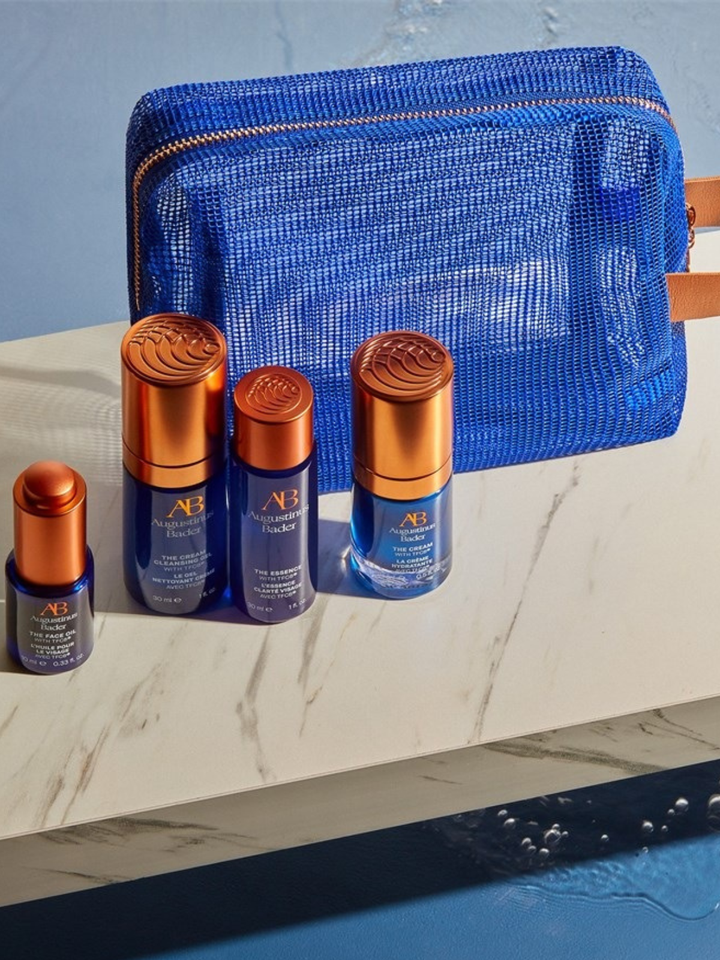 Set of skincare products with blue and orange packaging on a marble surface.