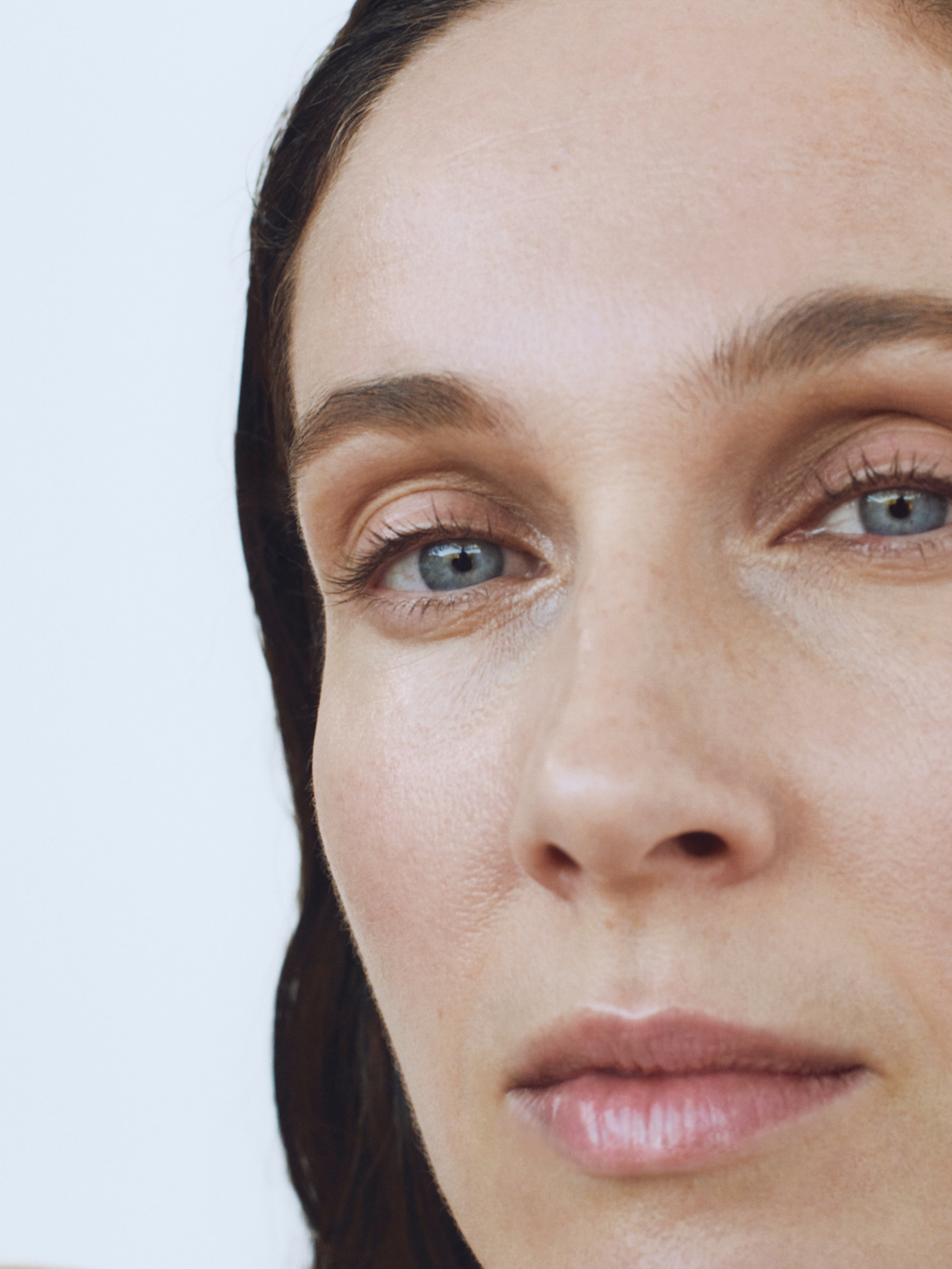 Close-up of a woman's face with a neutral expression on a light background