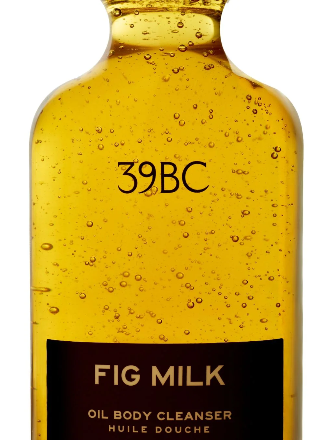 A close-up of a 39BC Fig Milk Oil Body Cleanser bottle filled with golden yellow oil and visible air bubbles, featuring a black label at the bottom on a white background.