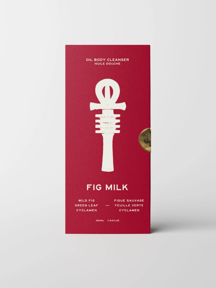 A tall rectangular red box for Fig Milk oil body cleanser by Wild Fig, featuring a large white Ankh symbol and product text, photographed on a light gray background.
