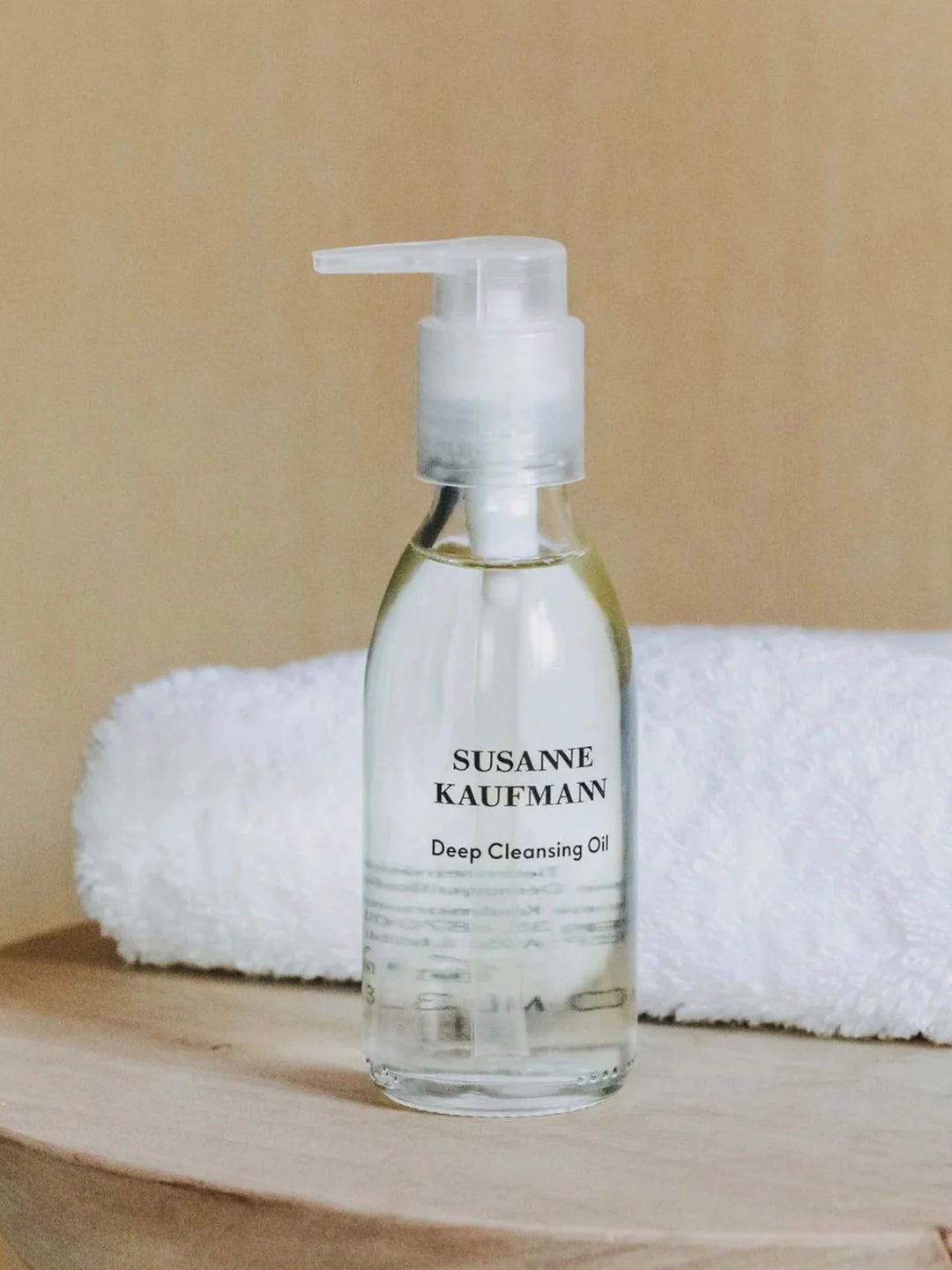 Bottle of Susanne Kaufman Deep Cleansing Oil on a wooden surface with a beige background